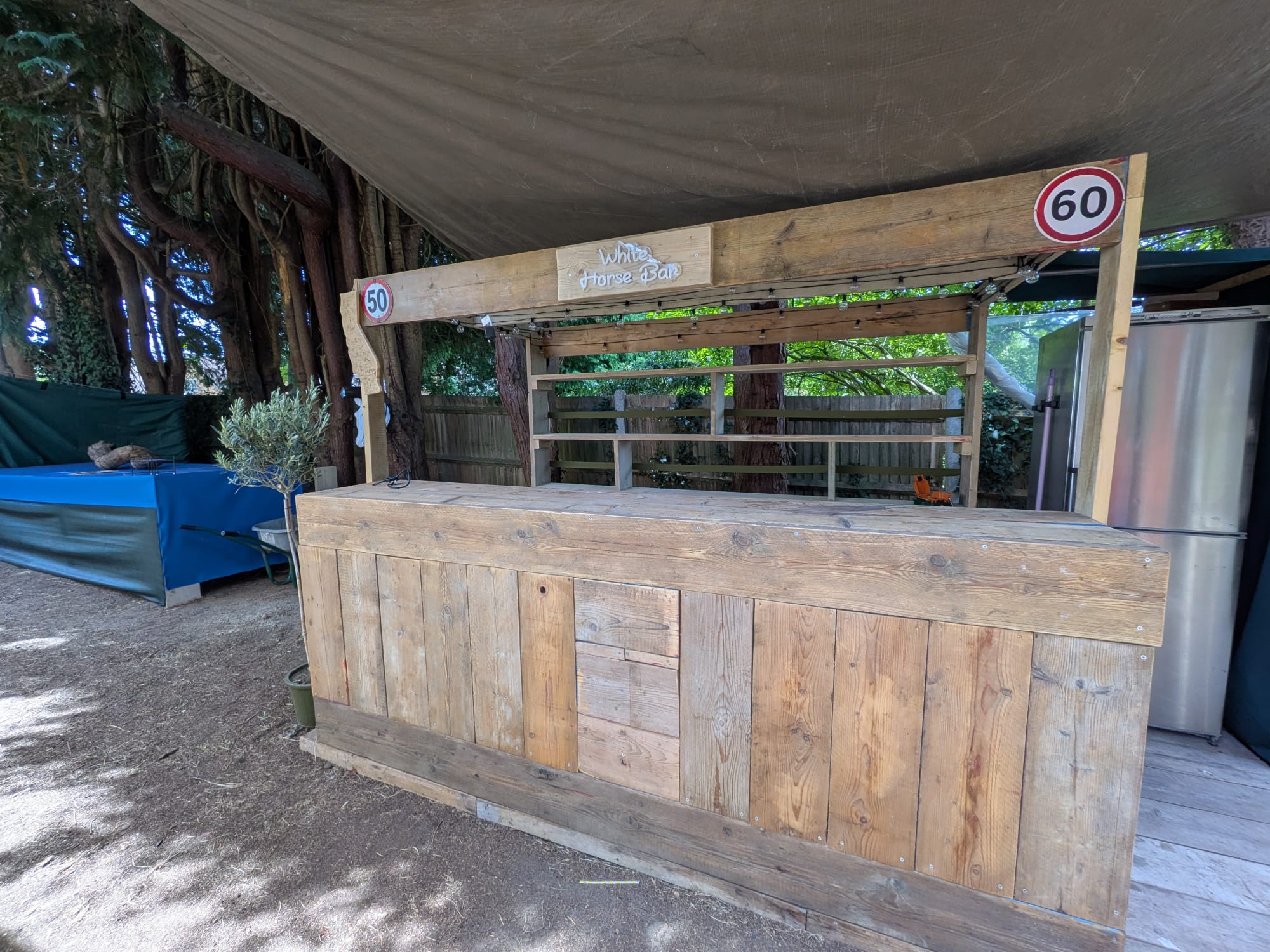 A handcrafted wooden garden bar under a canopy, with rustic timber cladding and a White Horse Bar sign